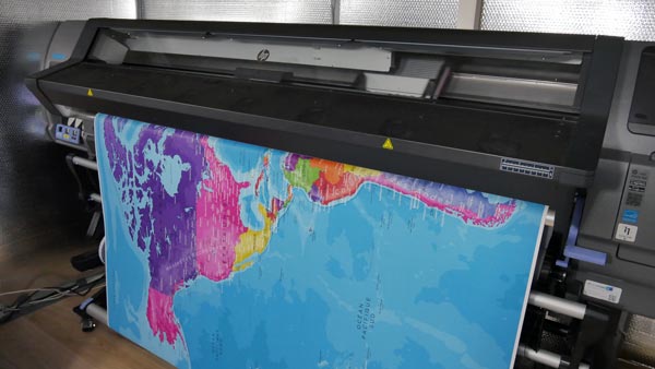 Stampa di una mappa geografica mondiale su grande plotter professionale.